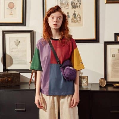 A young woman with red hair wearing multicolored casual clothing and glasses, showcasing stylish eyewear options at Monalisa Store. Perfect for trendy eyewear shopping and optical fashion needs.