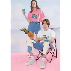 Young woman and man wearing trendy casual outfits with playful graphics, holding a pineapple and a beverage, perfect for summer and leisure.