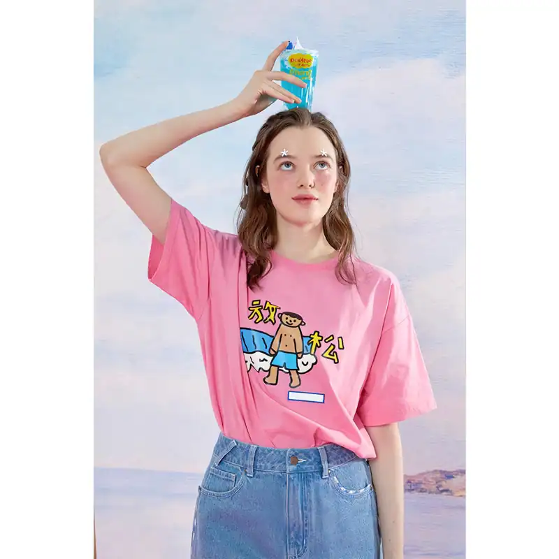 Young woman with water spray on her head, wearing casual pink graphic t-shirt and denim jeans, enjoying summer vibes and beach lifestyle, perfect for summer fashion and beach accessories.