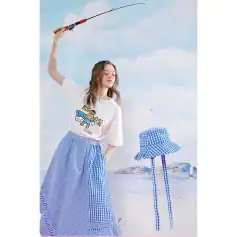 Young woman in trendy summer outfit holding fishing rod at beach, showcasing vibrant, stylish clothing for opt.