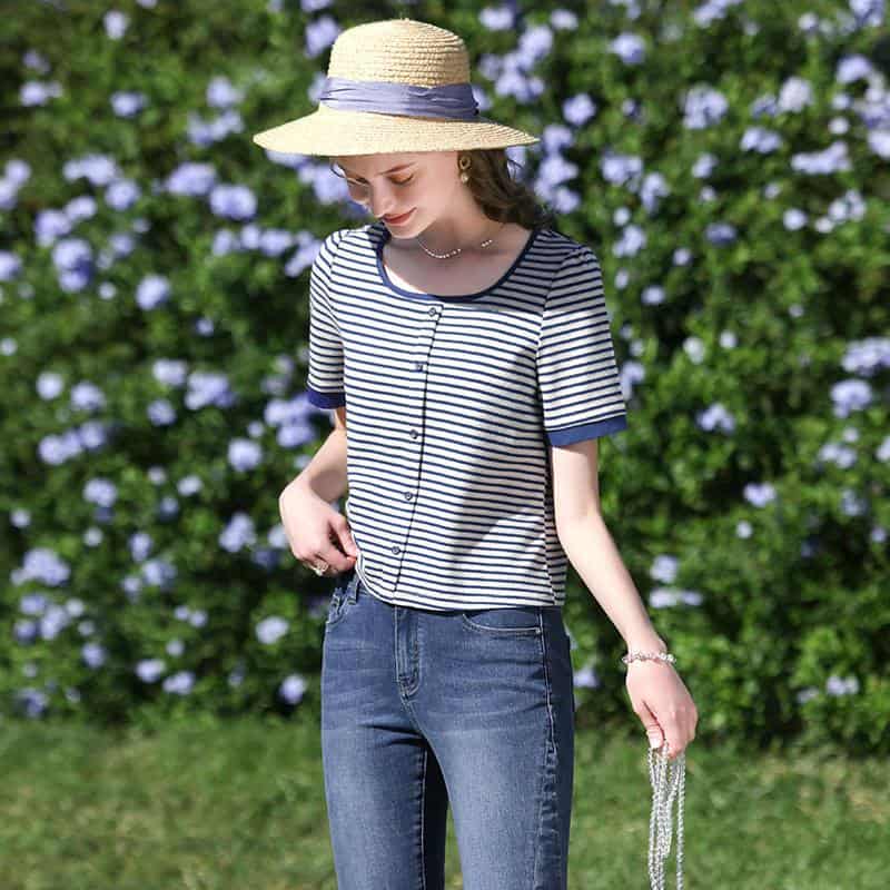 Stylish casual striped top with navy accents, paired with jeans, perfect for a sunny day look. Features button-up front and trendy accessories for a fashionable vibe.