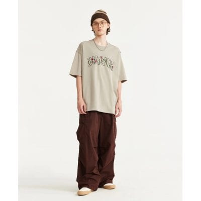 Casual oversized graphic t-shirt in beige with floral embroidery, paired with relaxed brown cargo pants for a trendy streetwear look. Perfect for stylish everyday wear.