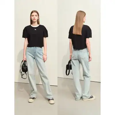 Young woman in black top and light denim jeans, holding a black handbag, showcasing trendy fashion look.