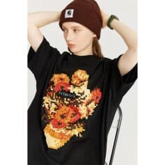 Young woman wearing a black graphic t-shirt, brown beanie, and casual accessories, showcasing trendy apparel from Monalisa Store for modern fashion followers.