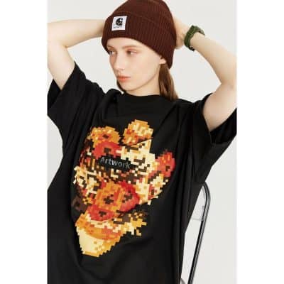 Young woman wearing a black graphic t-shirt, brown beanie, and casual accessories, showcasing trendy apparel from Monalisa Store for modern fashion followers.