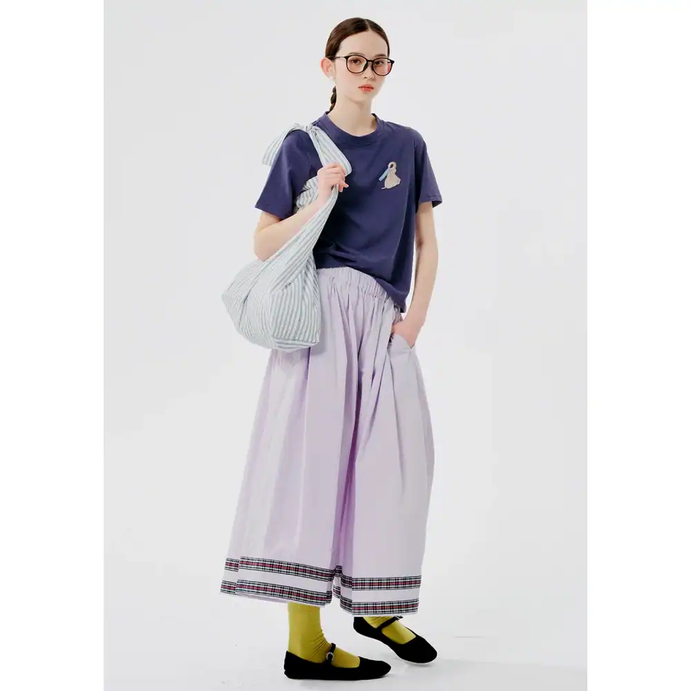 Stylish woman in casual outfit with glasses, tote bag, and wide pants for modern fashion and comfort.