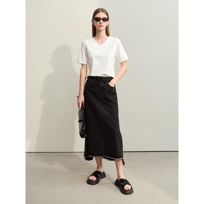 A stylish woman wearing a simple white V-neck T-shirt, black distressed denim maxi skirt, and chunky sandals, accessorized with black sunglasses and a clutch bag for a modern, casual look.