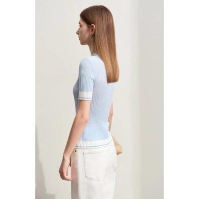 A woman wearing a light blue ribbed knit top with short sleeves and white accents, perfect for fashion-forward casual wear.