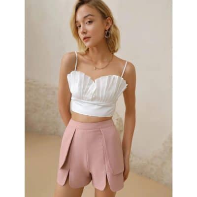 Elegant white pleated crop top with pink high-waisted shorts featuring unique scalloped hem design, perfect for summer fashion and casual wear.