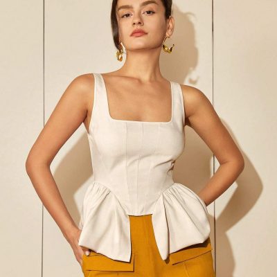 Elegant woman wearing stylish cream top and mustard pants, showcasing contemporary fashion and accessories.