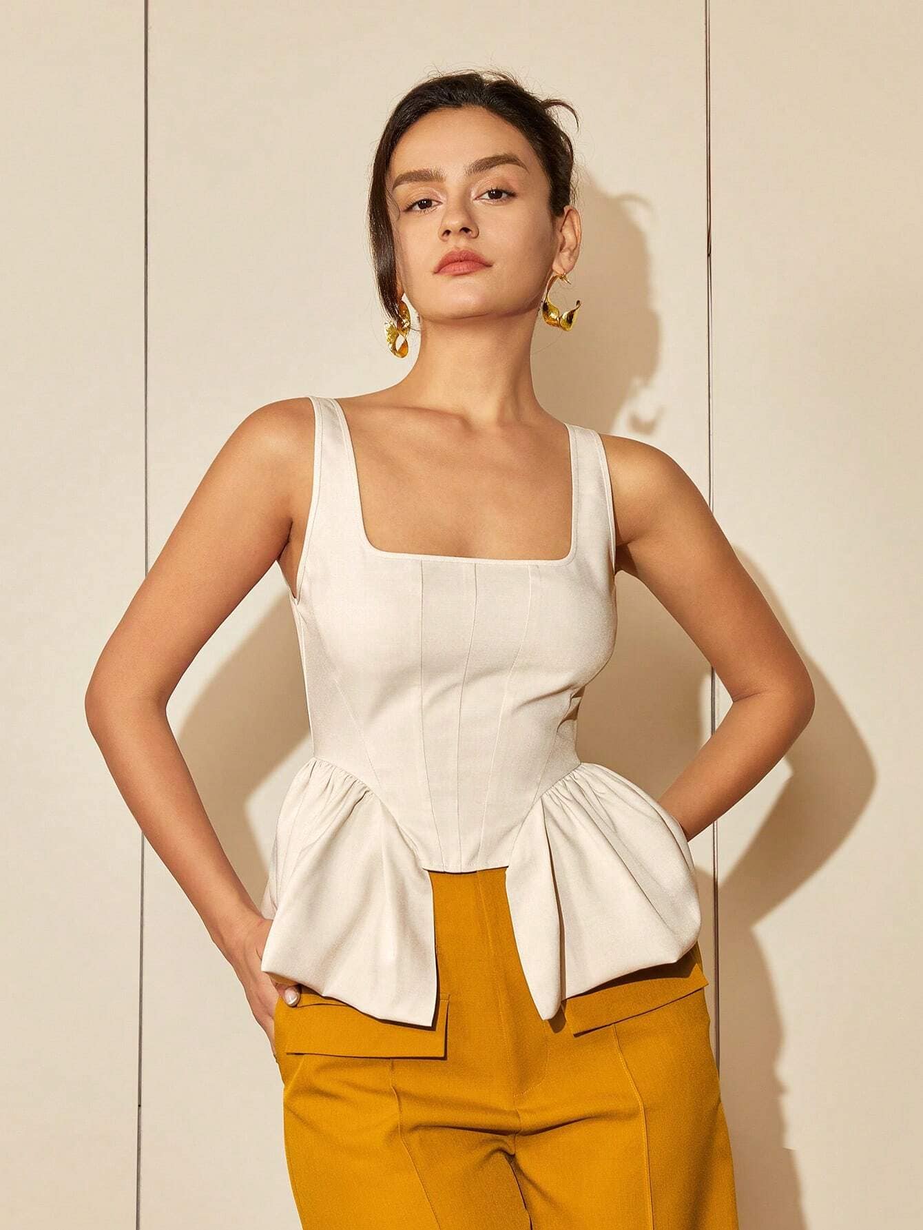 Elegant woman wearing stylish cream top and mustard pants, showcasing contemporary fashion and accessories.