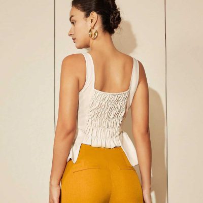 Stylish woman wearing a white smocked top and mustard yellow pants at Monalisa Medical Store, showcasing trendy clothing and accessories.