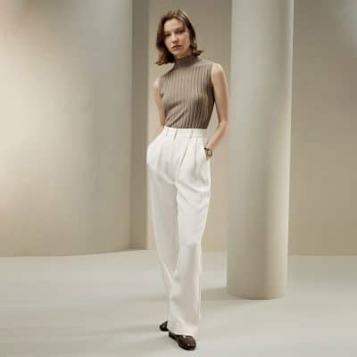 Chic women's fashion image featuring a beige sleeveless turtleneck and white high-waist trousers, ideal for professional or stylish casual outfits.