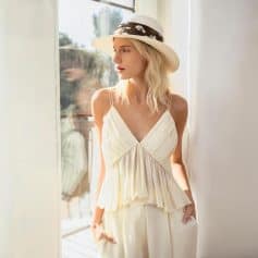 Young woman in elegant summer dress with sunhat, bright natural lighting, aiming at fashionable women's clothing and accessories for a lifestyle or fashion blog.