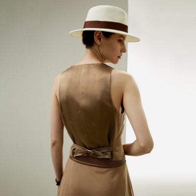 Stylish woman wearing a sophisticated sleeveless dress and a wide-brimmed hat, showcasing luxury fashion accessories available at Monalisa Store. Perfect for stylish shopping and exclusive fashion finds.