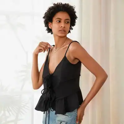 Stylish black sleeveless top with lace-up front and peplum detail, perfect for everyday wear or casual outings. Shop women's fashionable clothing at MonaLisa Store for a modern, chic look.