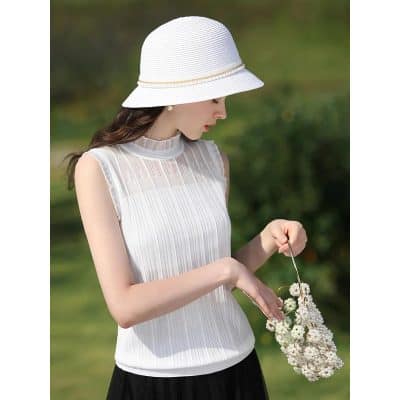 Stylish woman in a white dress and sun hat holding a floral handbag outdoors, perfect for summer fashion and accessories.