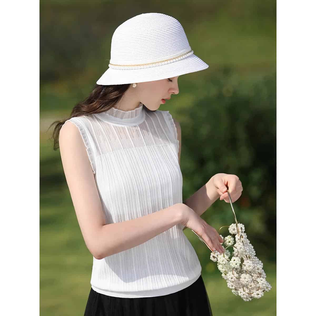 Stylish woman in a white dress and sun hat holding a floral handbag outdoors, perfect for summer fashion and accessories.