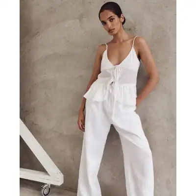 Elegant white sleeveless jumpsuit with adjustable tie front and wide-leg pants, perfect for modern fashion and comfort.