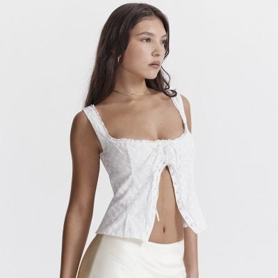 Elegant white women’s sleeveless top with eyelet embroidery and front tie detail, perfect for stylish summer or casual wear.