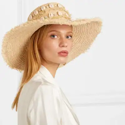 Elegant straw hat with seashell embellishments, perfect for summer or outdoor events. Stylish sun protection accessory for women.