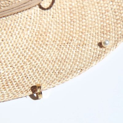 Elegant straw sun hat with pearl embellishments for stylish sun protection and accessory appeal. Perfect for summer outings and outdoor events.