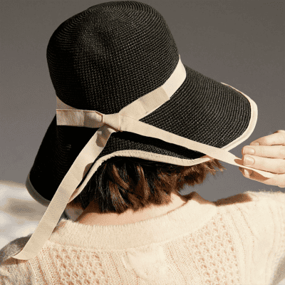 Elegant black sun hat with wide brim and beige ribbon, perfect for sun protection and fashion, ideal for outdoor activities and beach days.