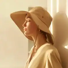 Close-up of a woman wearing a stylish beige wide-brim hat, ideal for sun protection and fashionable look, perfect for outdoor sunny days and summer fashion.