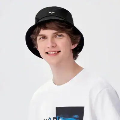 Casual young man with black bucket hat and trendy white T-shirt, exemplifying modern street style and fashion.