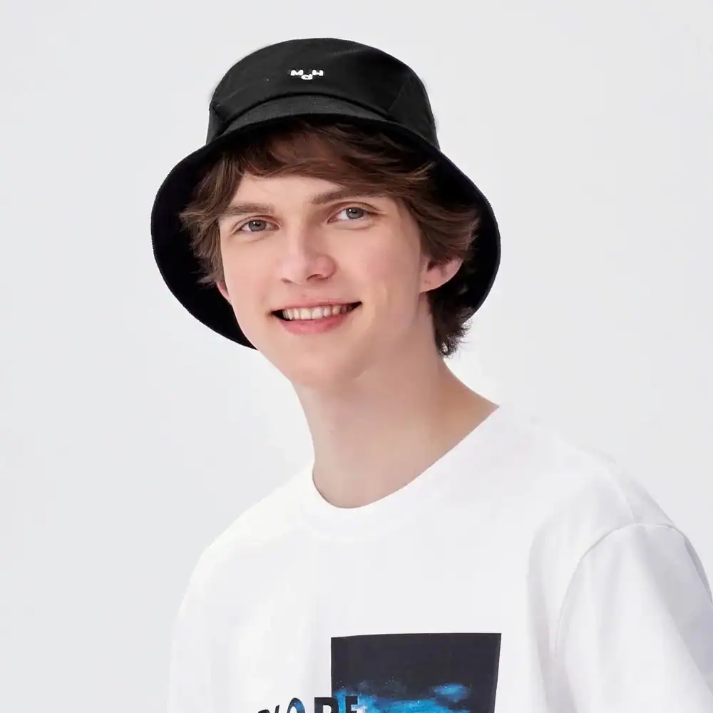 Casual young man with black bucket hat and trendy white T-shirt, exemplifying modern street style and fashion.