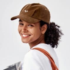 Close-up of a smiling woman wearing a trendy brown cap, ideal for both men and women. Perfect for outdoor, casual, and fashion-forward looks, available at Monalisa Store.