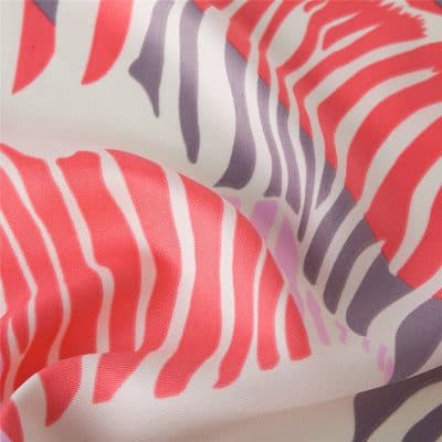 Close-up of colorful zebra pattern in coral, purple, and white, showcasing smooth fabric texture ideal for fashion accessories or apparel.