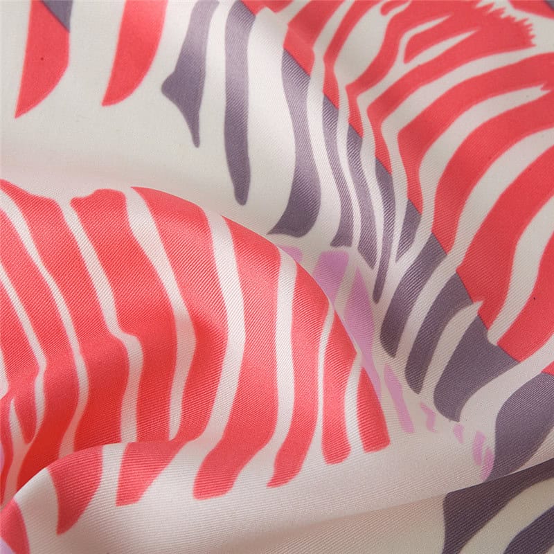 Close-up of colorful zebra pattern in coral, purple, and white, showcasing smooth fabric texture ideal for fashion accessories or apparel.