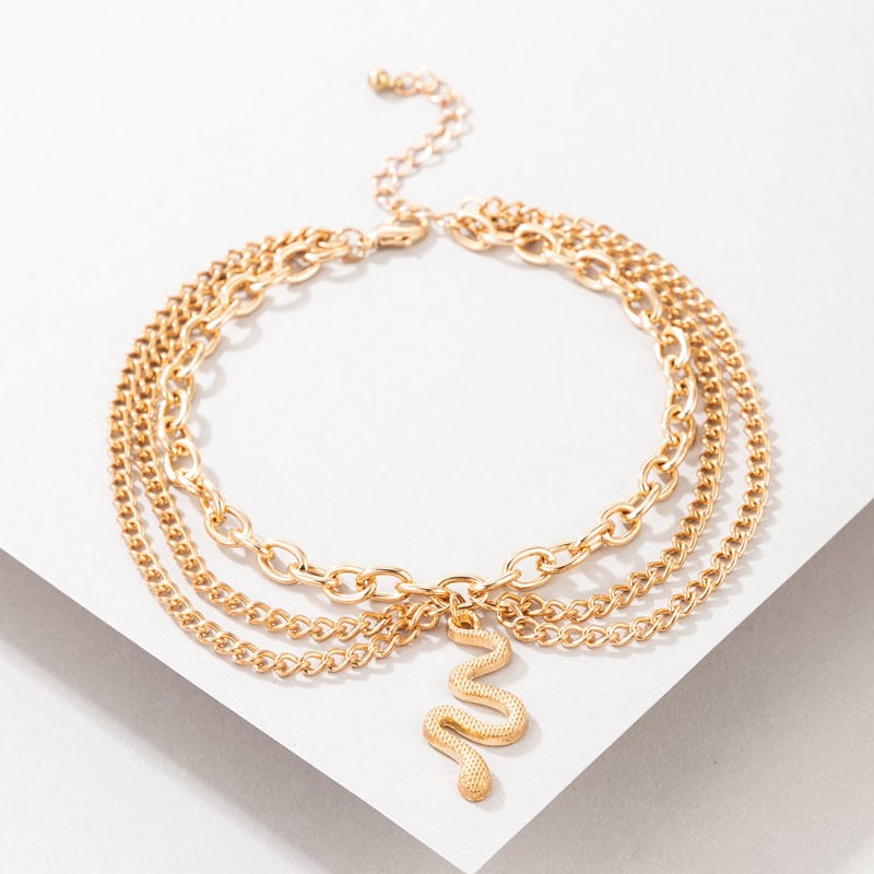 Elegant layered gold snake pendant necklace with multiple chain styles for women. Perfect accessory for fashion and statement jewelry enthusiasts.