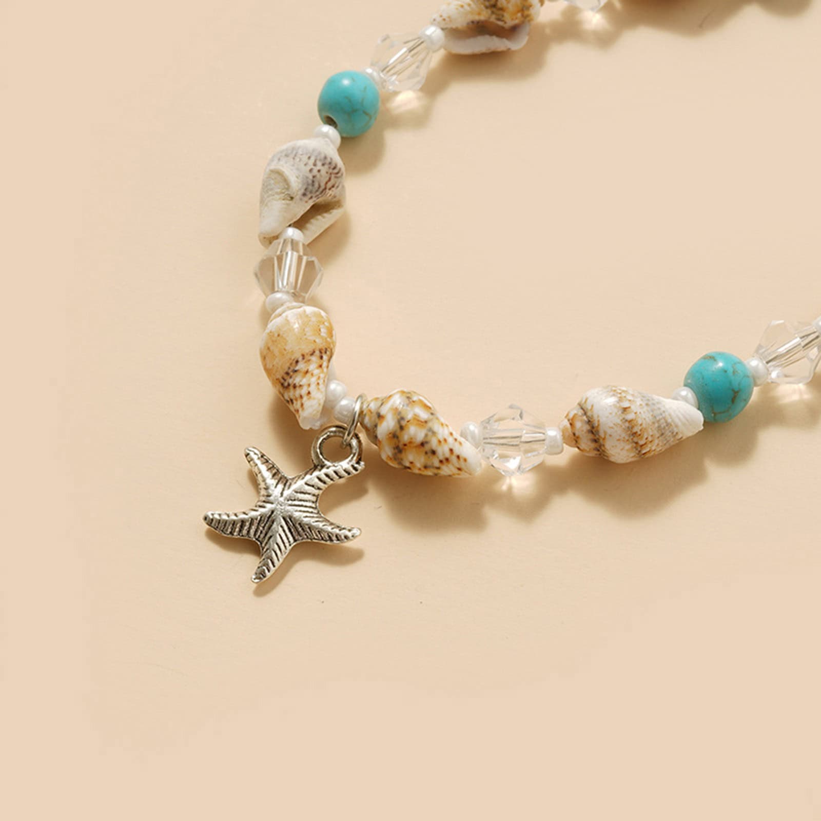 Beach-inspired jewelry with seashells, turquoise beads, and starfish charm, perfect for summer beachwear or ocean-themed fashion accessories.