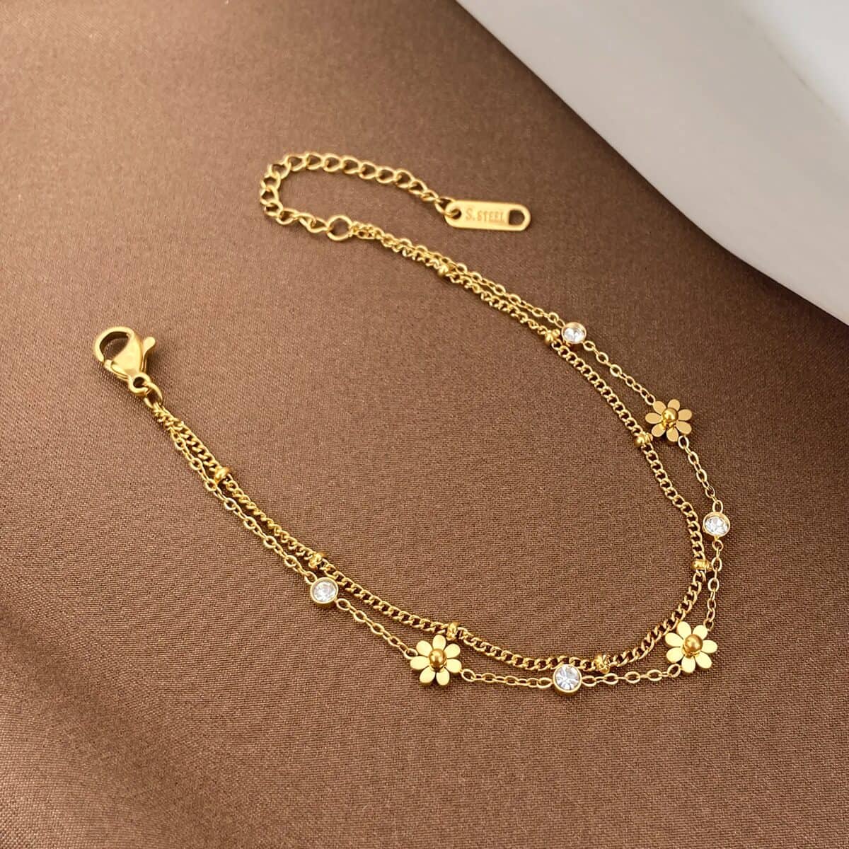 Gold bracelet featuring flower motifs and sparkling crystals, designed for women's fashion jewelry. A chic accessory to elevate any outfit, ideal for gifting or personal collection.