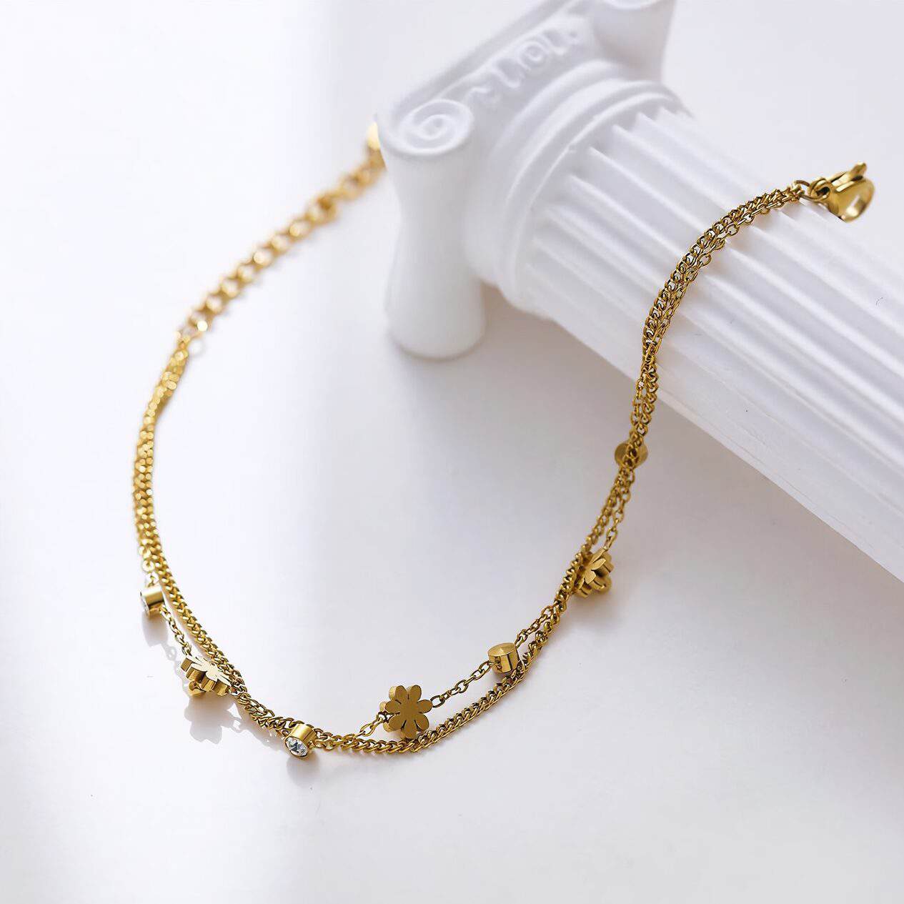 Delicate gold-toned layered necklace with floral and cubic accents, perfect for formal or casual occasions, highlighting stylish jewelry pieces.
