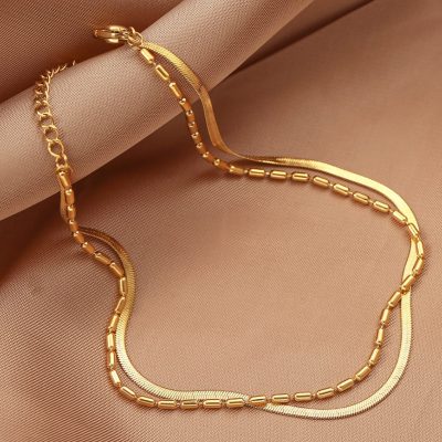 Gold necklace on a beige satin background, showcasing a sophisticated, luxurious design with a mix of chain styles, ideal for fashion accessories and fine jewelry collection.