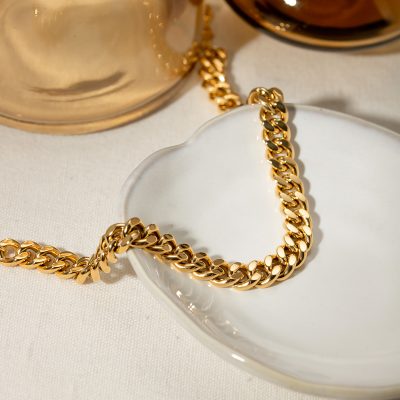 A luxurious gold chain necklace displayed on a white ceramic dish, perfect for jewelry lovers seeking stylish accessories. High-quality, timeless jewelry piece for everyday wear or special occasions.