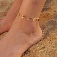 Gold anklet jewelry for women, perfect for beach or casual wear, featuring small dangling charms, lightweight and stylish. Ideal accessory for enhancing summer outfits and beach looks.