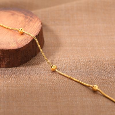 Beautiful gold necklace with spherical accents displayed on wooden platform for stylish jewelry showcase. Perfect for women seeking high-quality gold jewelry.