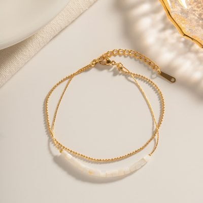 Delicate gold chain necklace with white pearl beads, perfect for stylish and sophisticated women. Ideal for adding a touch of elegance to any outfit.