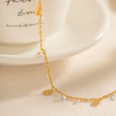 Delicate gold chain bracelet with small crystal accents and heart charms, showcased on a white dish, perfect for stylish gift ideas or personal elegance.