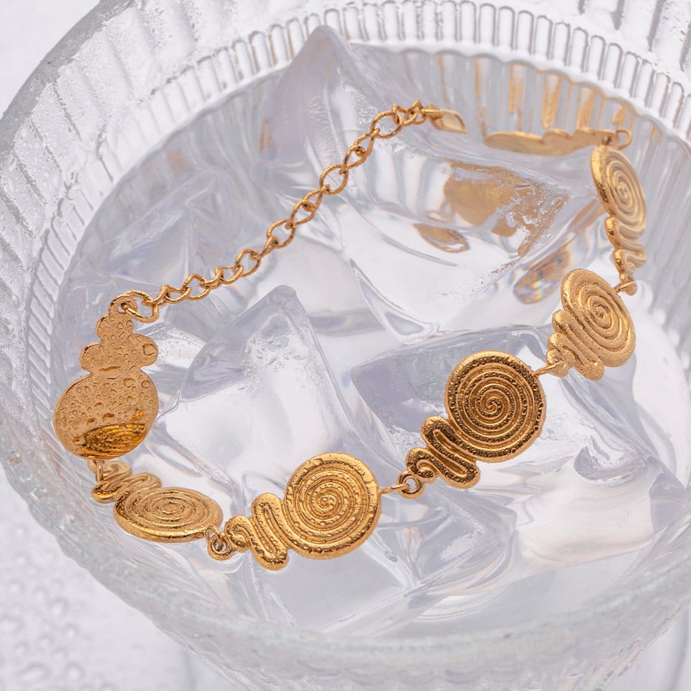 Gold spiral bracelet with intricate swirling design, perfect for fashionable accessories and luxury jewelry collections.