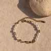 Gold and freshwater pearl bracelet on sandy surface with shadow, perfect for stylish jewelry and accessory shopping.