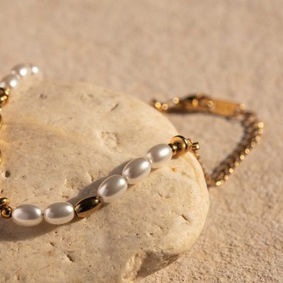 Beautiful pearl and gold bracelet displayed on a textured sandy surface, highlighting luxury jewelry with a sophisticated design perfect for special occasions or stylish accessorizing.