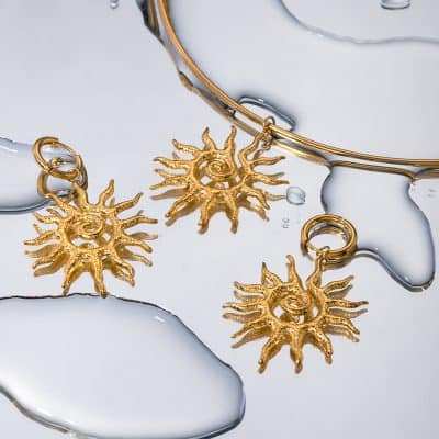Elegant gold sun-shaped pendant with intricate details. Perfect for stylish accessories and matching with various outfits. Luxurious jewelry at Monalisa Store.