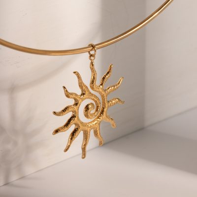 Gold sun-shaped pendant with a textured finish, hanging from a delicate gold necklace. Elegant jewelry designed for sun and nature lovers, perfect for everyday wear or special occasions.