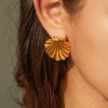 Close-up of a gold shell-shaped earring worn on a woman's ear, showcasing luxurious jewelry design with high-quality craftsmanship for a stylish, modern look.