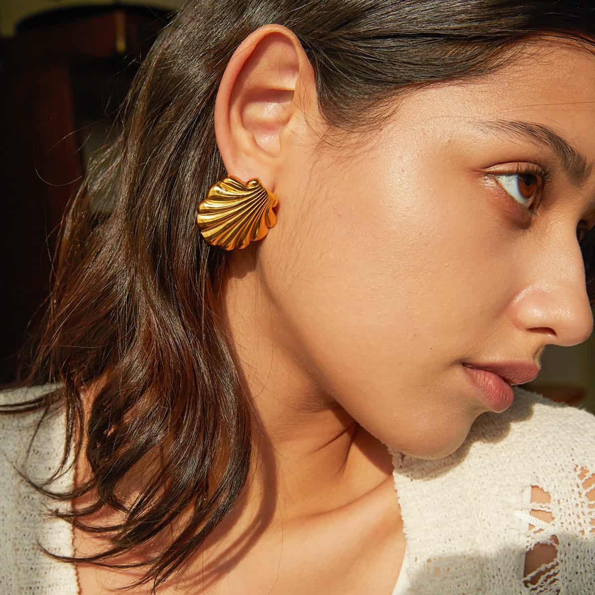 Close-up of a woman wearing a stylish gold shell-shaped earring, showcasing jewelry for women, fashion accessories, and luxury jewelry from Monalisa Store.